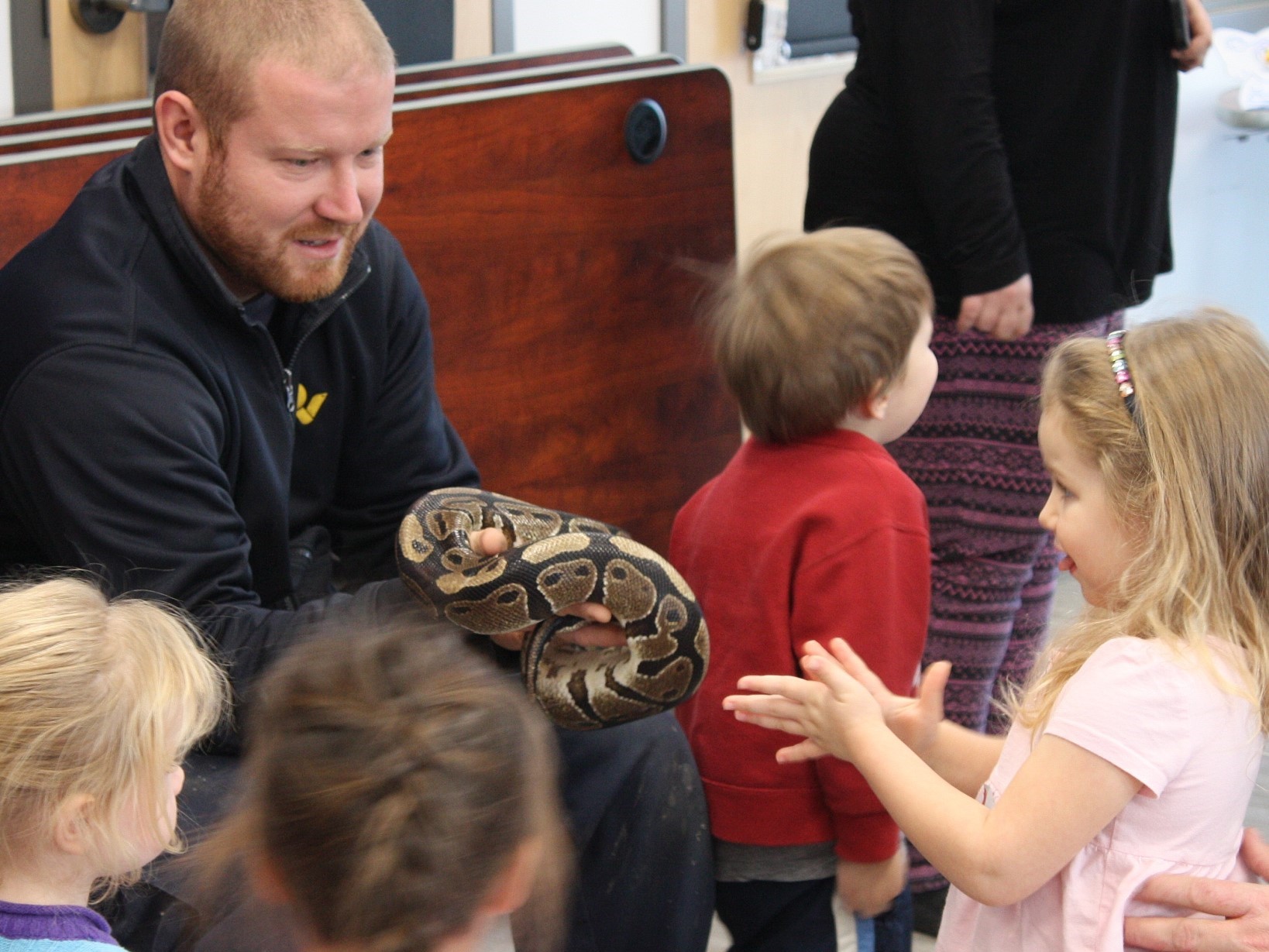 zoo staff holding a snake with children looking on